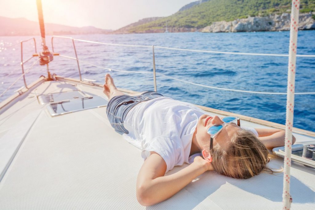 Teenager boy sunbathing on a sailing boat in Greek islands CV